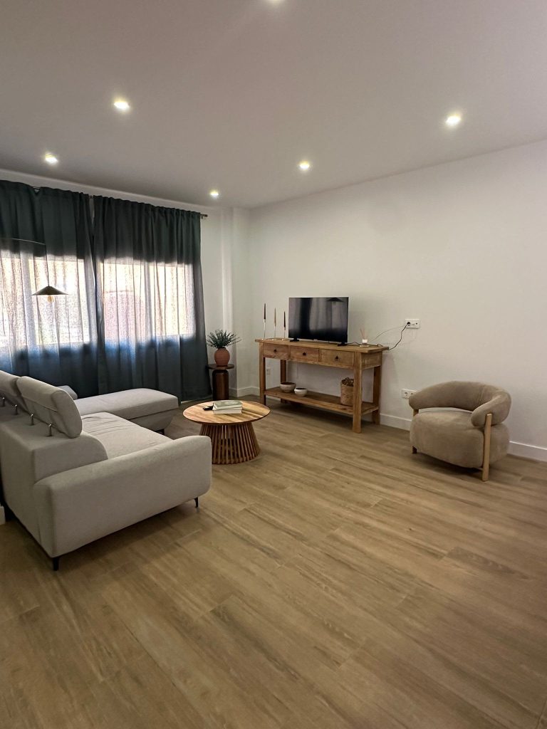 Salón amplio con sofá gris y mueble de madera rústica